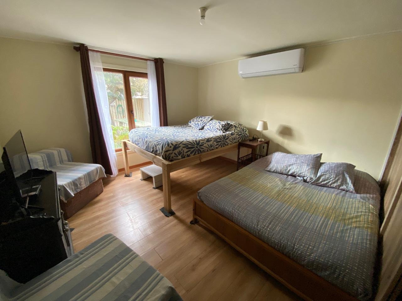 Dormitorio principal amplio con camas, climatización y acceso al exterior